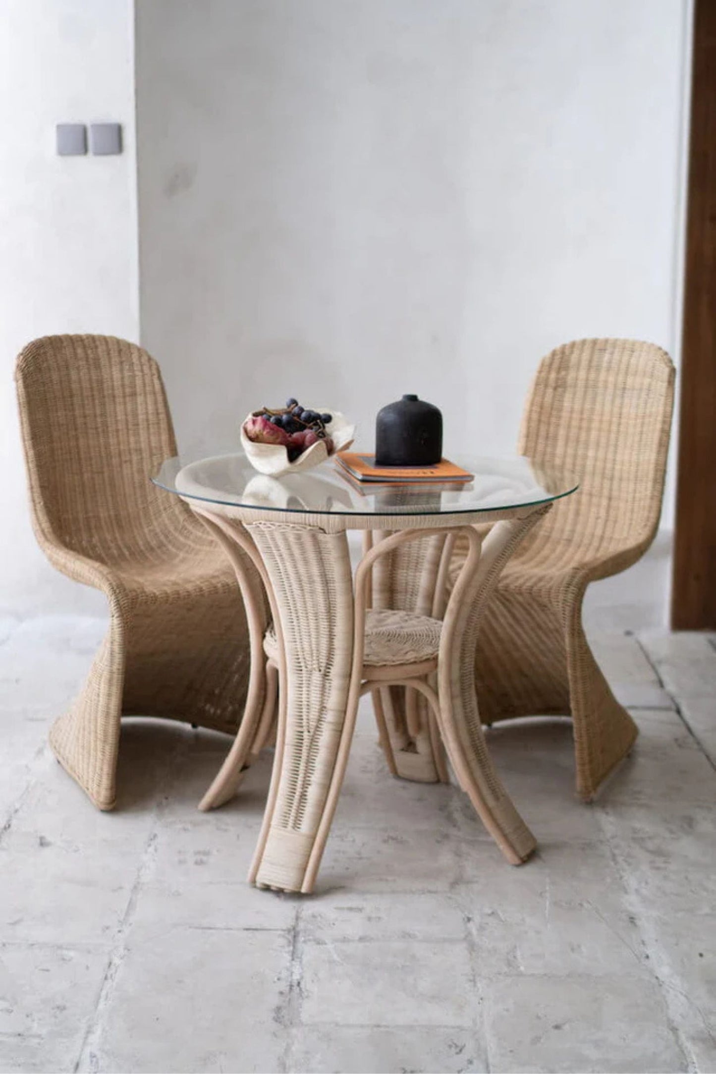 Oriana Ori round rattan table with woven shelf and braided legs, topped with thick glass, showcasing handcrafted natural rattan design and artisanal details