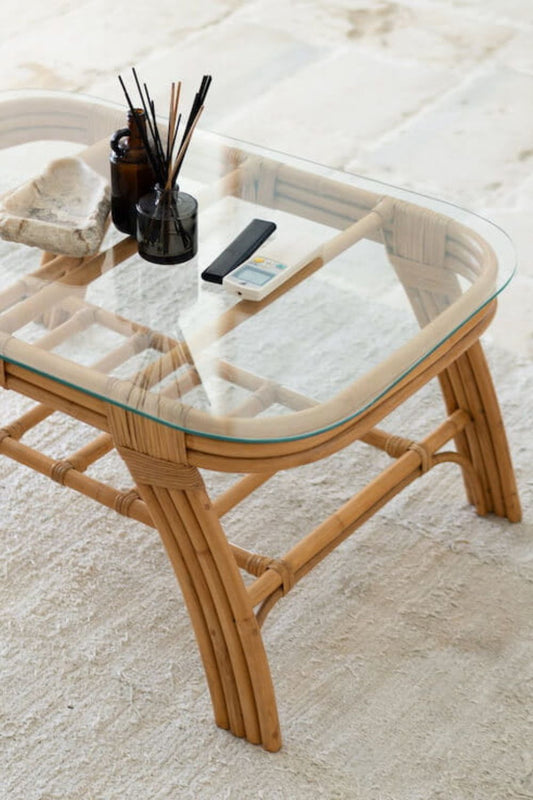 Handcrafted Sali rattan table with thick glass top and central shelf, featuring opalescent natural tones and elegant, unique design.