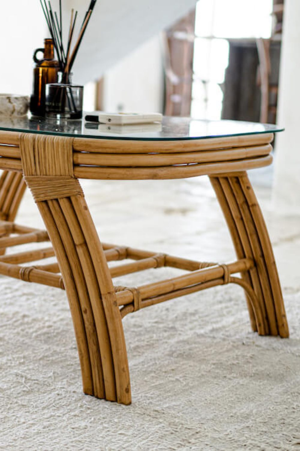 Handcrafted Sali rattan table with thick glass top and central shelf, featuring opalescent natural tones and elegant, unique design.