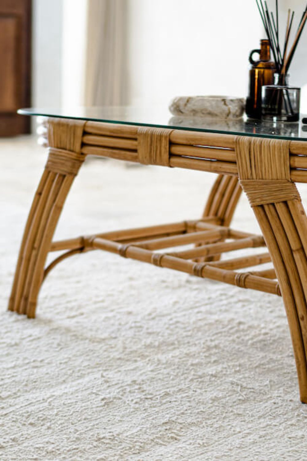 Handcrafted Sali rattan table with thick glass top and central shelf, featuring opalescent natural tones and elegant, unique design.