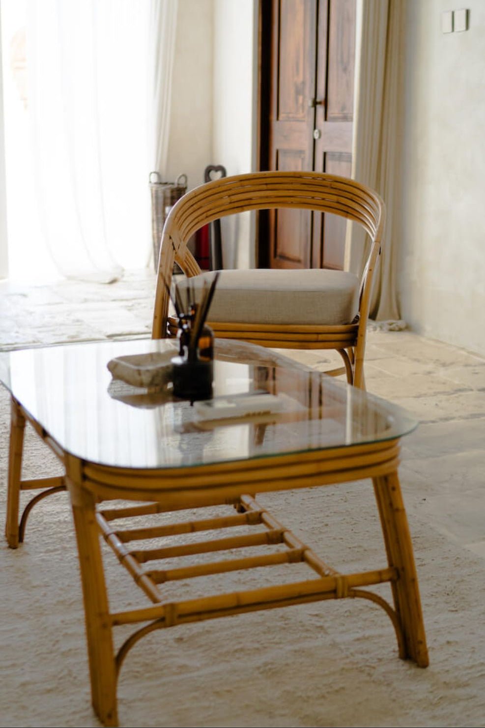 Handcrafted Sali rattan table with thick glass top and central shelf, featuring opalescent natural tones and elegant, unique design.