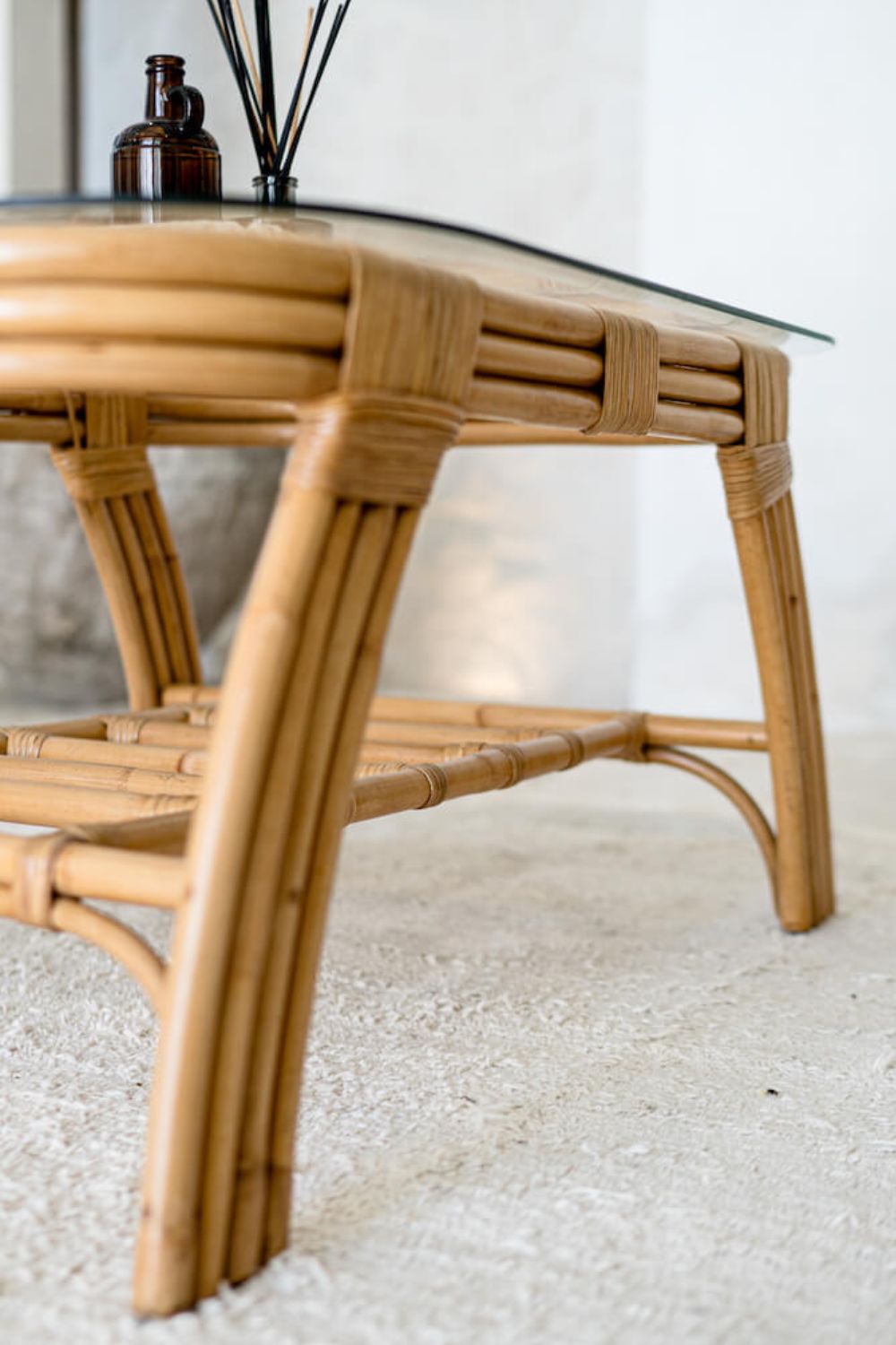 Handcrafted Sali rattan table with thick glass top and central shelf, featuring opalescent natural tones and elegant, unique design.