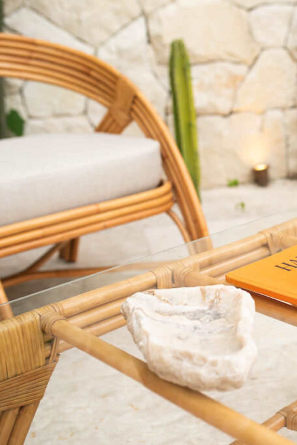 Handcrafted Sali rattan table with thick glass top and central shelf, featuring opalescent natural tones and elegant, unique design.