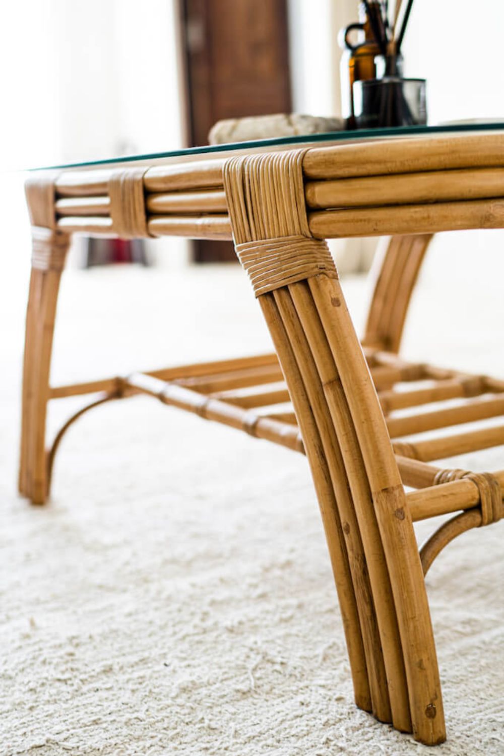 Handcrafted Sali rattan table with thick glass top and central shelf, featuring opalescent natural tones and elegant, unique design.