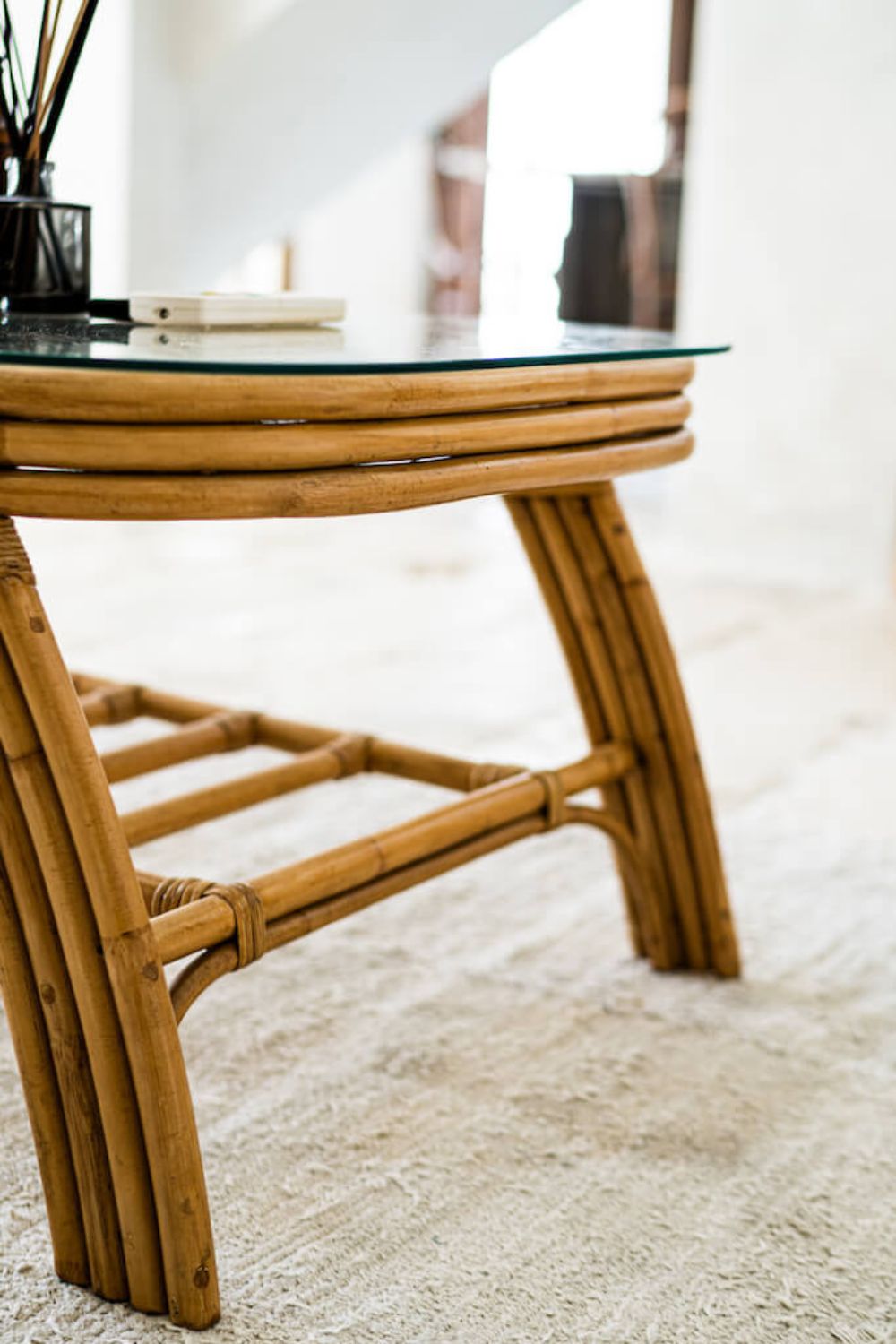 Handcrafted Sali rattan table with thick glass top and central shelf, featuring opalescent natural tones and elegant, unique design.