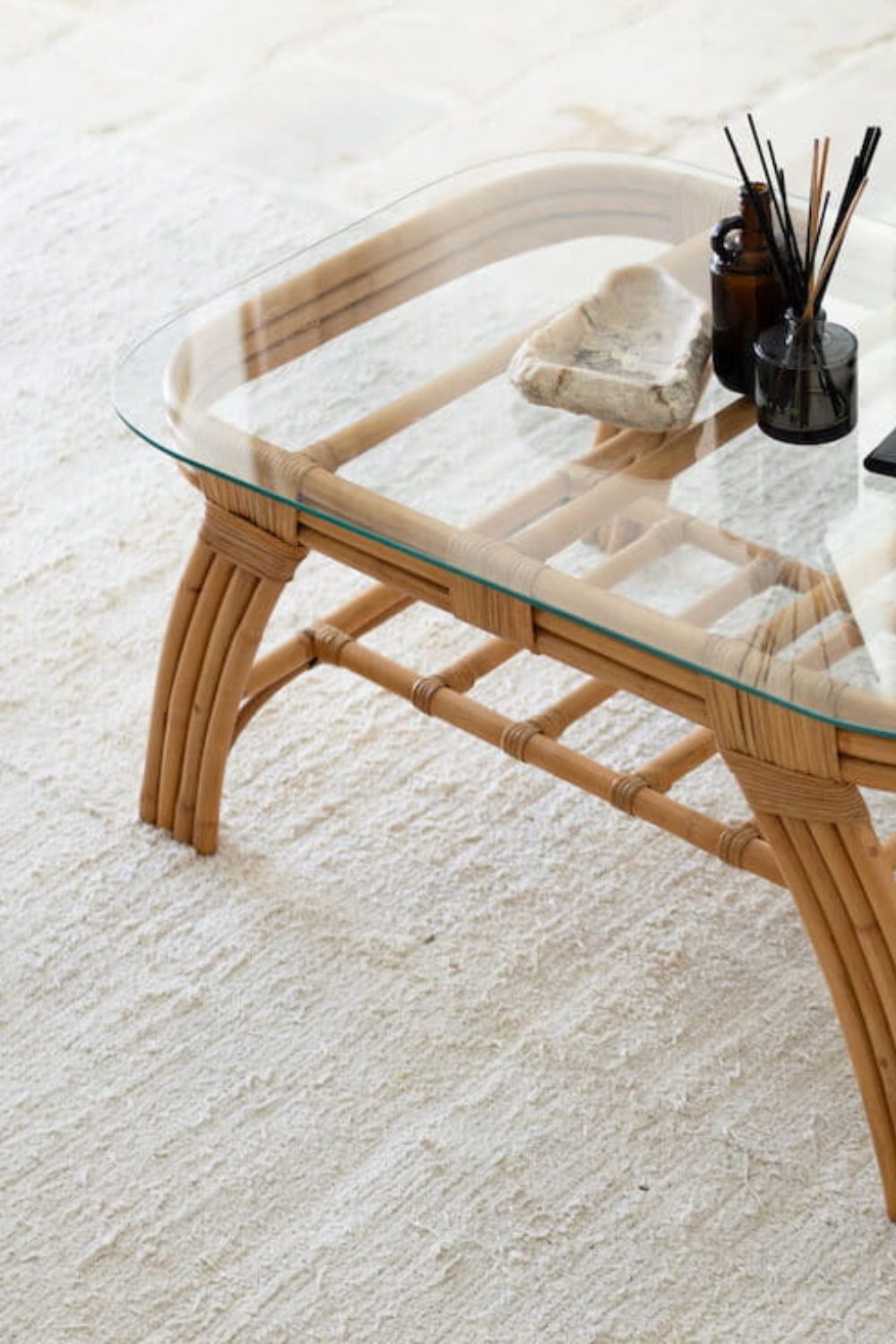 Handcrafted Sali rattan table with thick glass top and central shelf, featuring opalescent natural tones and elegant, unique design.