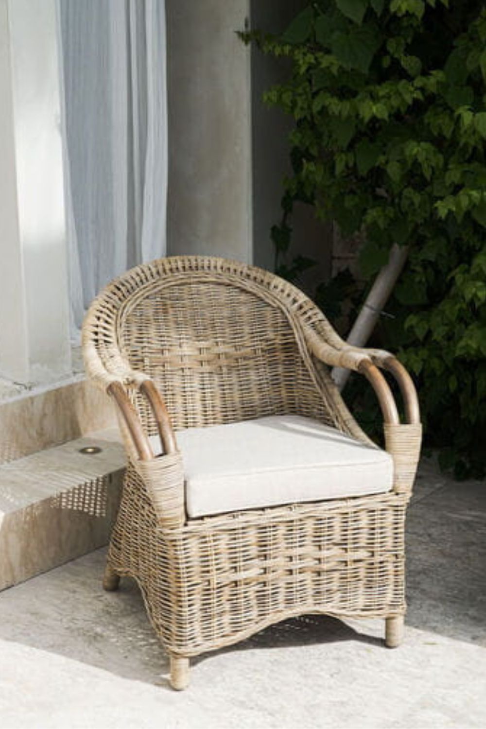 Handcrafted Tyo rattan armchair with curved armrests and woven headrest in natural autumn tones